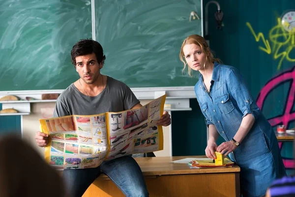 A teacher holds a magazine in a classroom from "Fack ju Göhte".